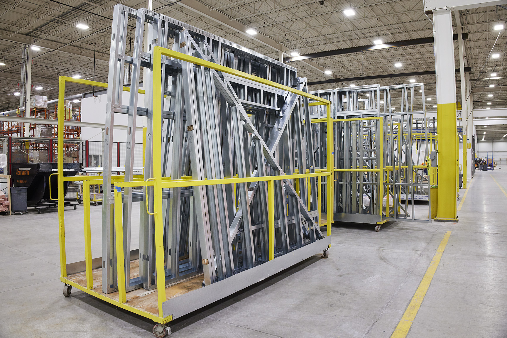 Steel frames on wheeled racks in manufacturing plant