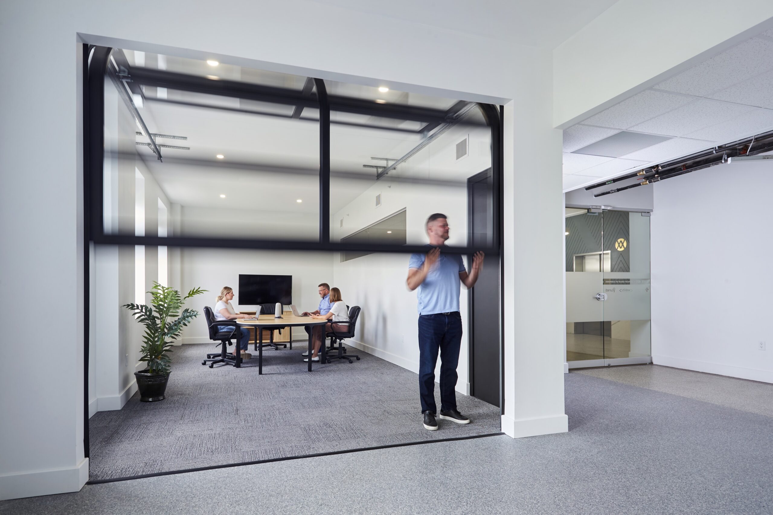 WHQ 4th Floor0722_511505 Man opens overhead door to modern look meeting room space