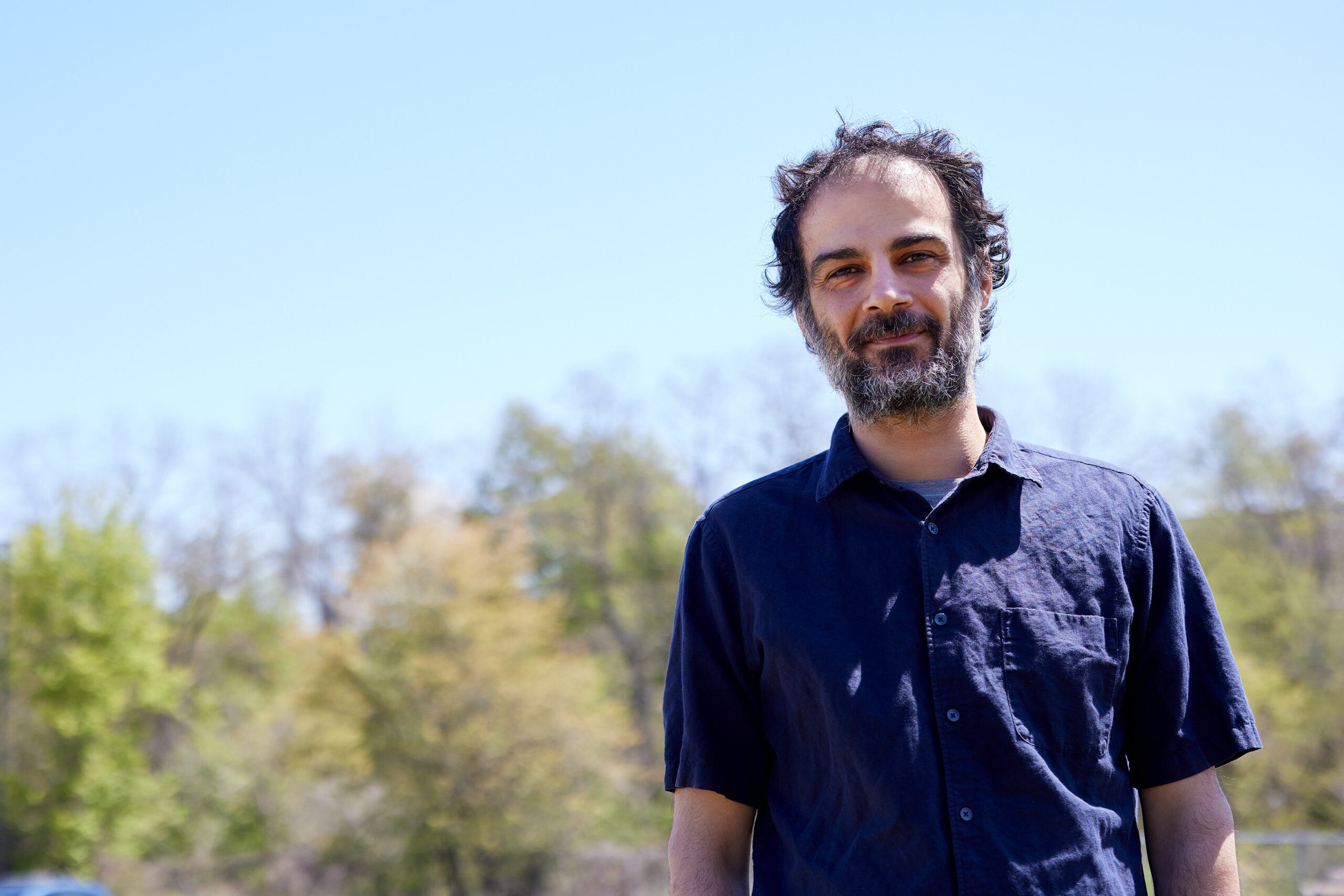 Amin Ahmadi, outdoors in a field looking into camera