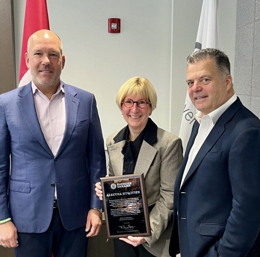 Two men and women dress in suits hold an award and smile for a photo.