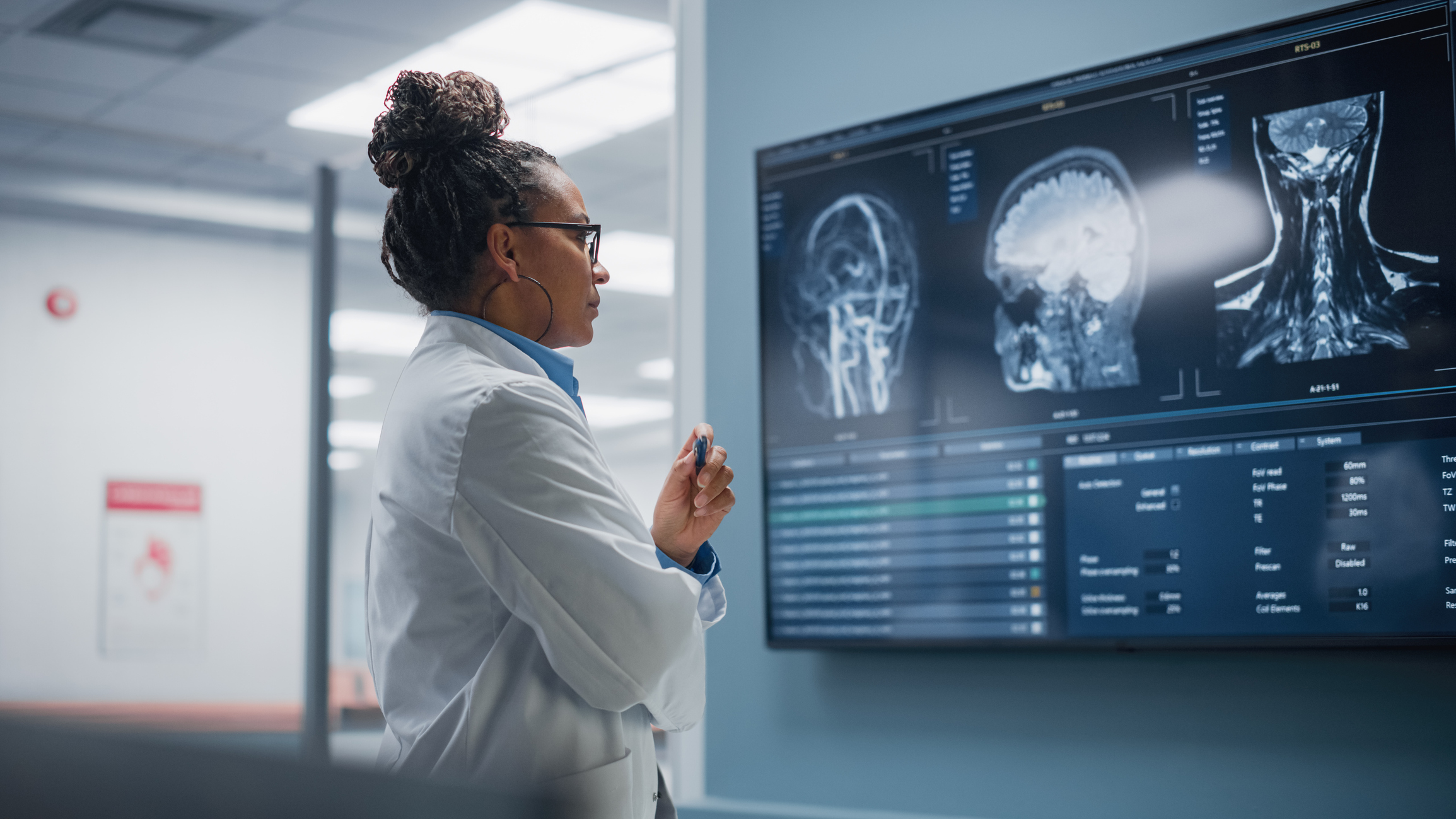 Confident Black Female Neurologist Looks at TV Screen with MRI Scan with Brain Images, Thinks about Sick Patient Treatment Method. Saving Lives